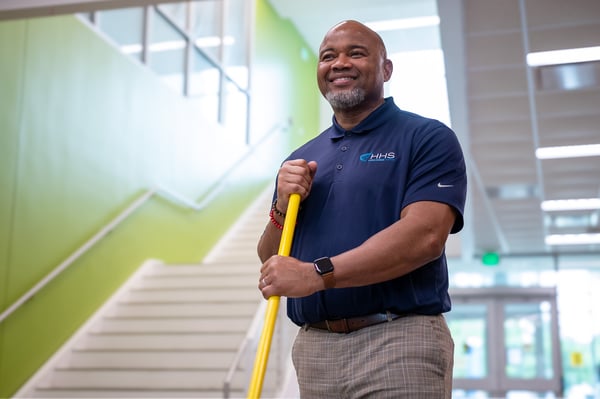 Smiling housekeeper with mop handle