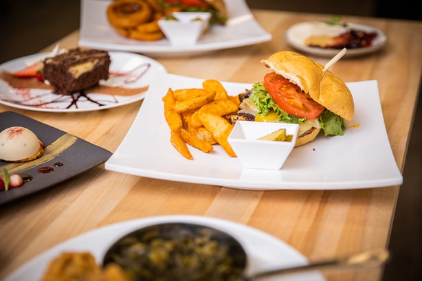 burger and fries on wooden table, surrounded by other dishes