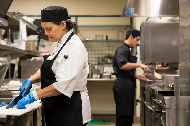 two hhs chefs preparing food in an industrial kitchen