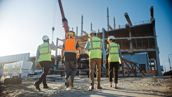 Construction staffing partner and site worker shaking hands on job site, signaling hiring partnership and project support.