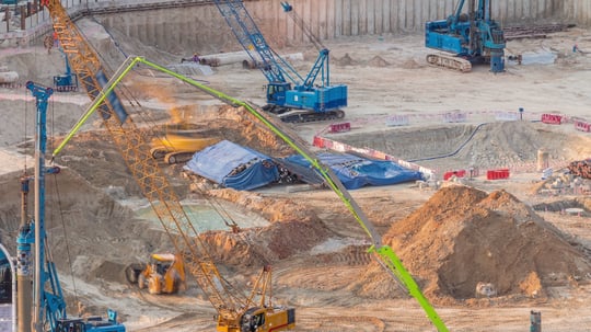 Aerial view of a partially constructed job site with minimal crew, illustrating delays and understaffed construction projects.