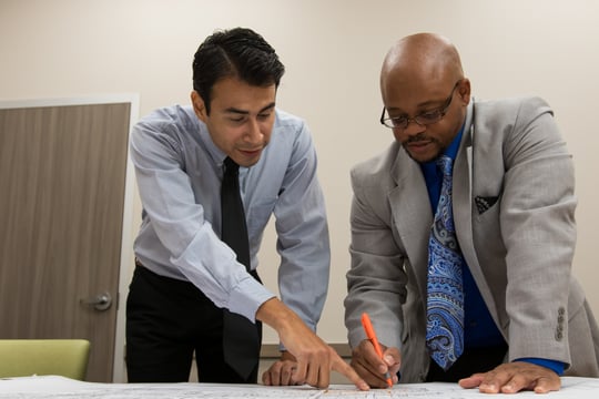 Two professionals reviewing documents together in a collaborative setting, symbolizing career mentorship and transition support at HHS