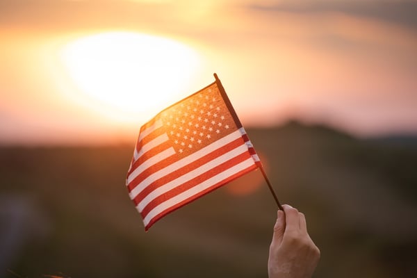 Close-up of a hand holding an American flag at sunset, symbolizing military transition and new beginnings