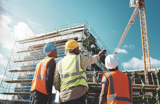 Three construction supervisors assessing a site and coordinating build plans, representing structured staffing solutions.